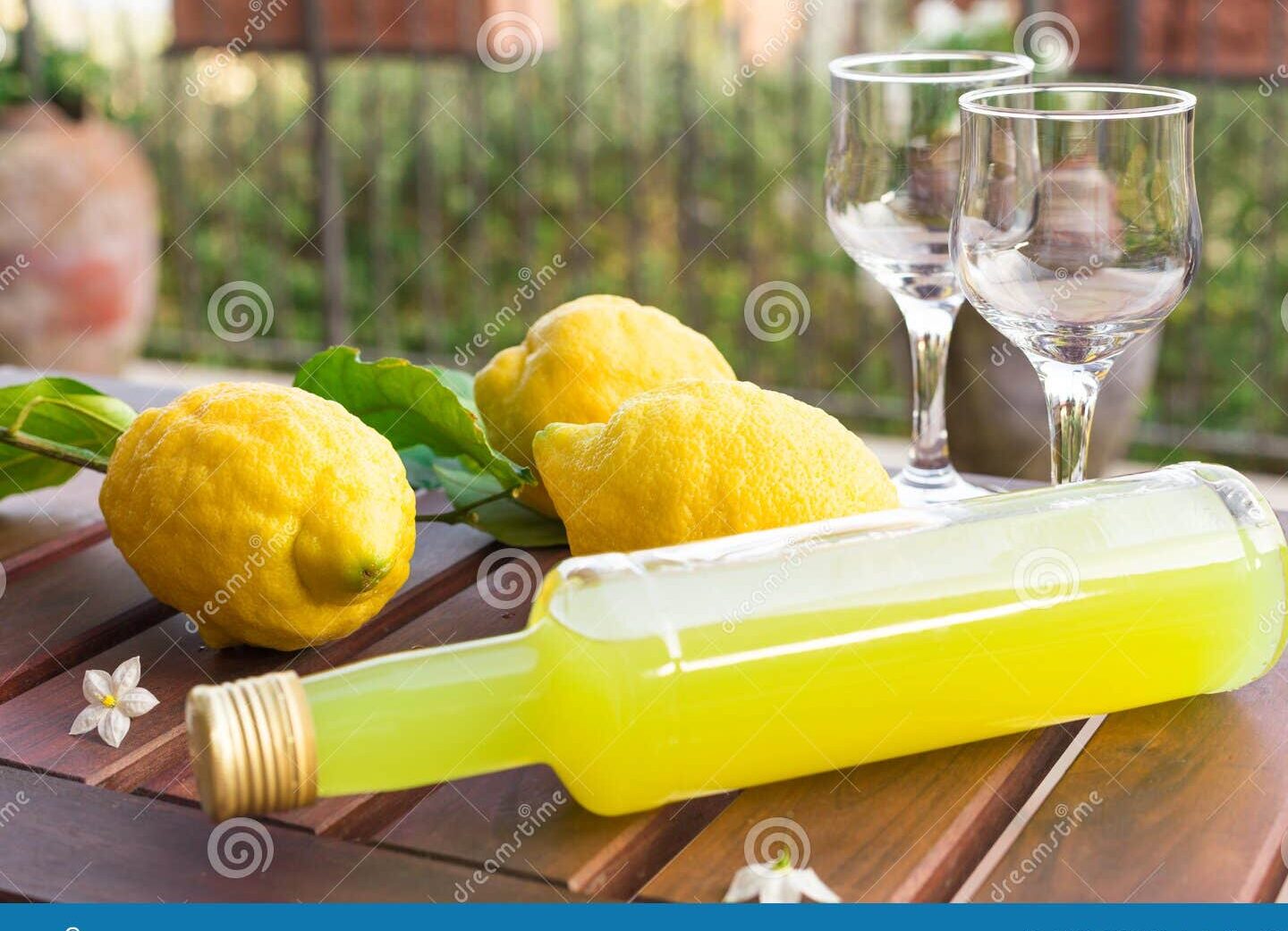 botella de limoncello con limones frescos alrededor