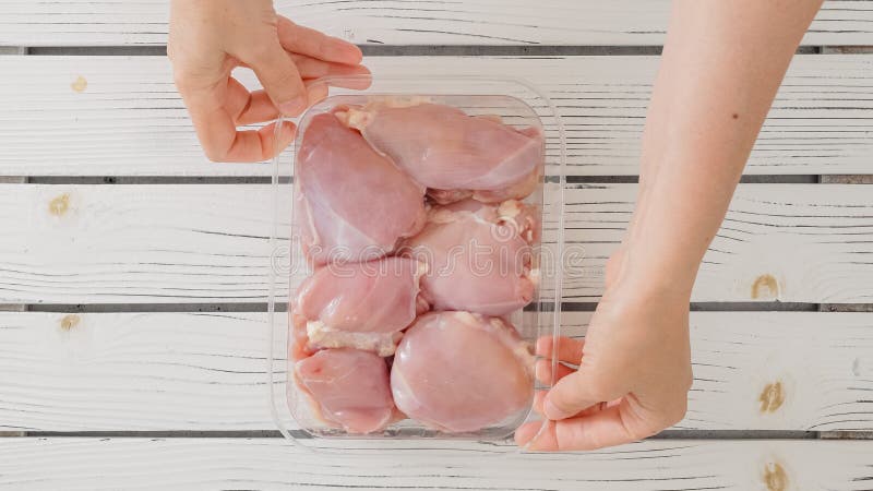 manos deshuesando muslo de pollo crudo