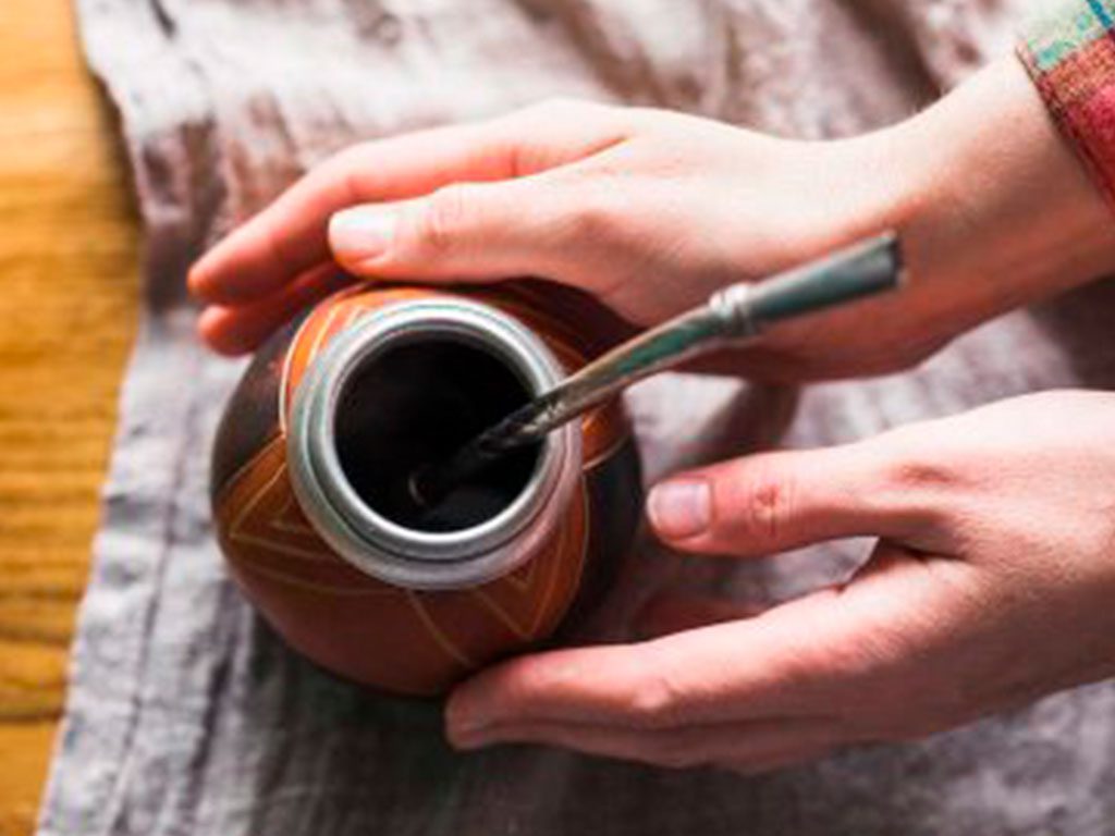 manos preparando mate con bombilla de calabaza