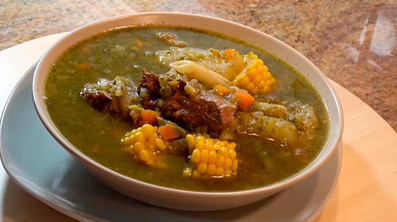 un plato de sopa humeante con carne y choclo