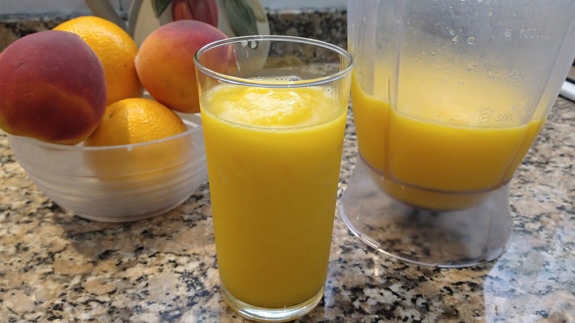 un vaso con un licuado de durazno y naranja